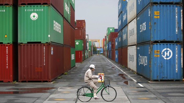 A worker rides a bicycle in a container area at a port in Tokyo