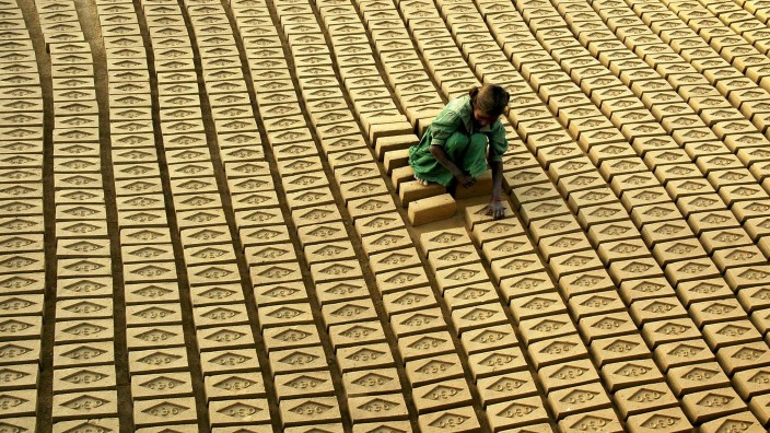 Indian child labourer arranges bricks at a brick factory in Tharvai village