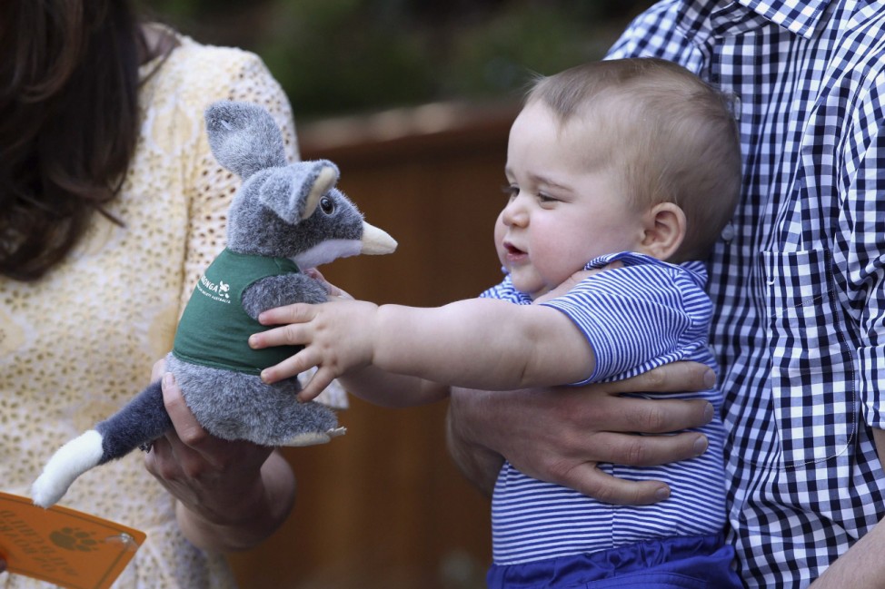 Britain's Prince William holds Prince George as he chews a sticker during a visit to Taronga Zoo in Sydney