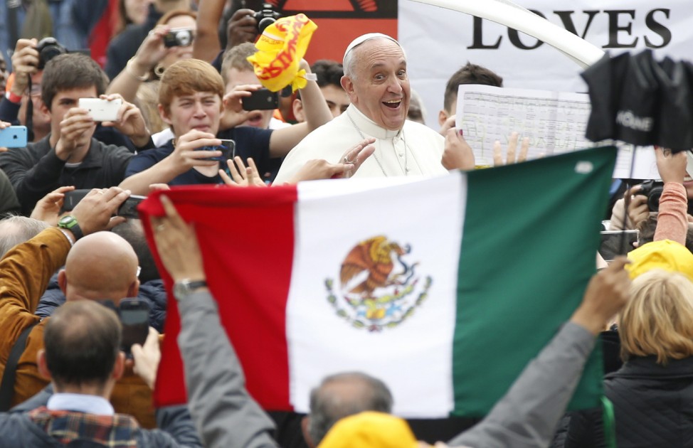 Pope Francis smiles to a faithful holding a Mexican flag as he leads the general audience in Saint Peter's Square at the Vatican