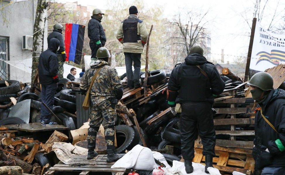Pro-Russian men stand guard at a barricade near the police headquarters in Slaviansk
