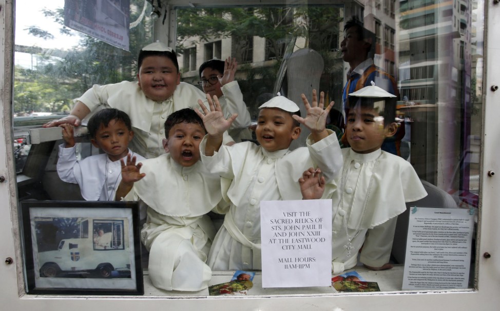 Children wearing Pope's cassocks ride a Popemobile that was used by Pope John Paul II in his 1995 visit to Manila, during a parade in Quezon city