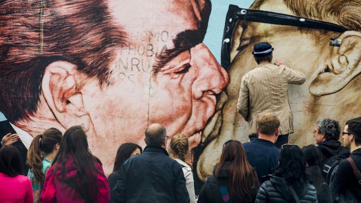 Artist Dimitry Vrubel cleans his mural 'Fraternal Kiss' at the East Side Gallery in Berlin