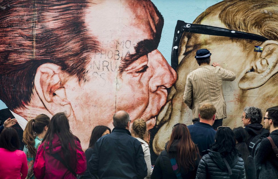 Artist Dimitry Vrubel cleans his mural 'Fraternal Kiss' at the East Side Gallery in Berlin