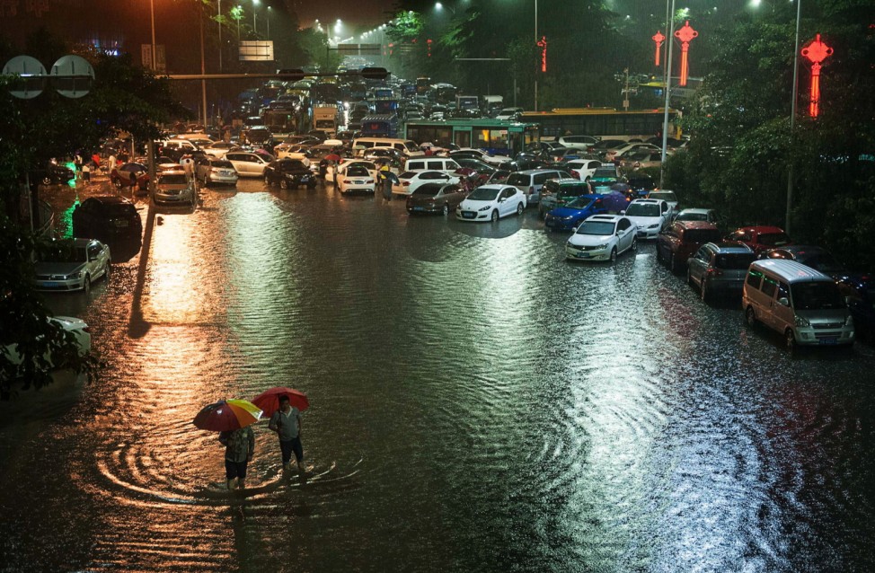 People walk along a flooded street as traffic is blocked in the rain in Shenzhen