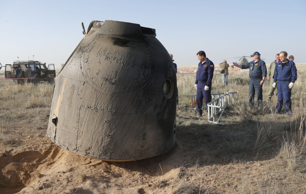 Rescue team members arrive as the Russian Soyuz TMA-11M space capsule rests on the ground shortly after landing in Dzhezkazgan, Kazakhstan