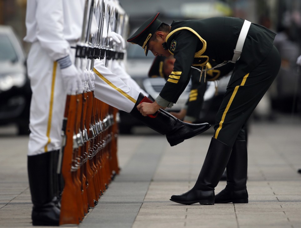 Members of an honour guard clean their boots as they get ready for a welcoming ceremony for the visiting Portugal's President Anibal Cavaco Silva, outside the Great Hall of the People in Beijing