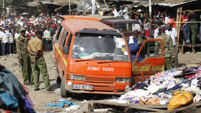 Policemen inspect a damaged public transport van wrecked at the scene of a twin explosion at the Gikomba open-air market for second hand clothes in Nairobi