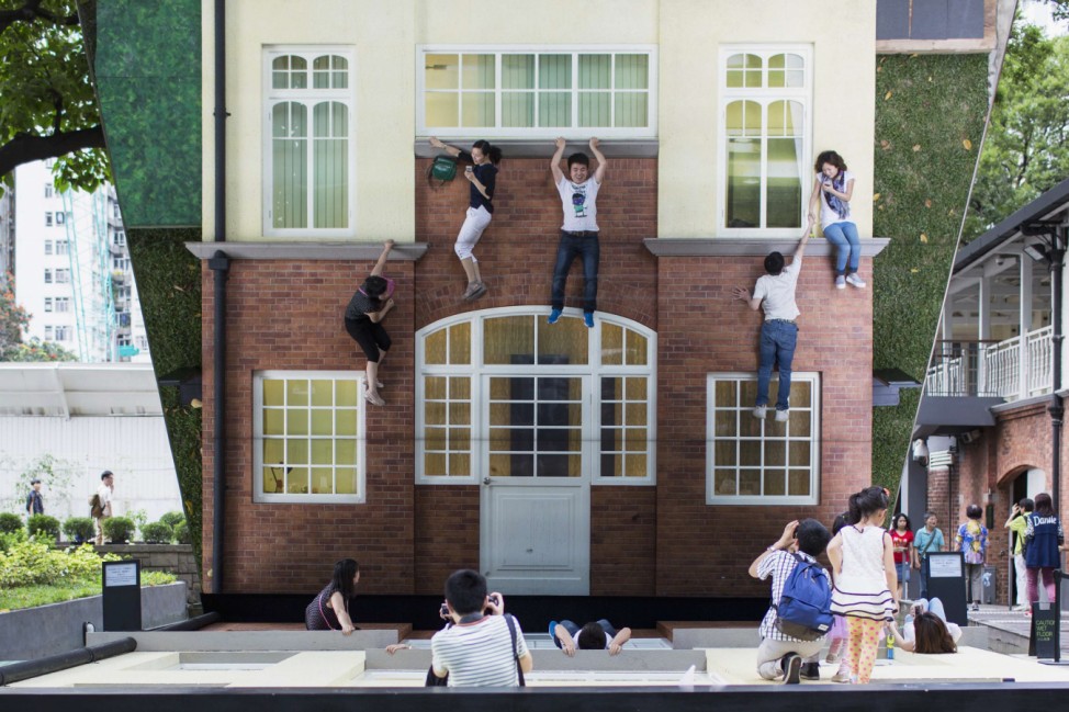 Visitors pose on Argentine artist Leandro Erlich's optical illusion installation 'Batiment - Oi!' in Hong Kong