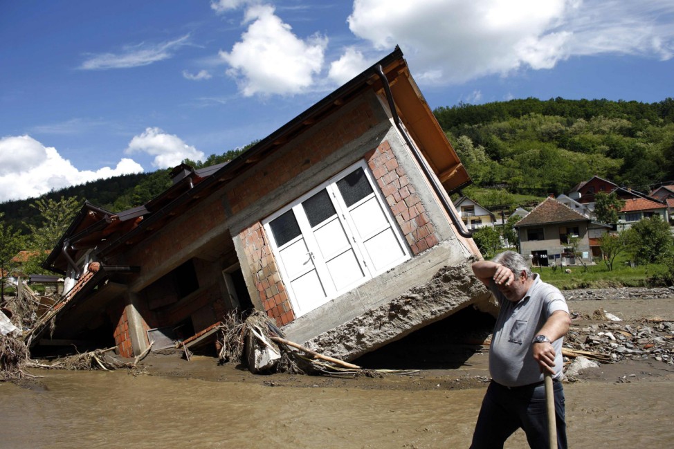A man reacts near a house tilted by floods in the village of Krupanj