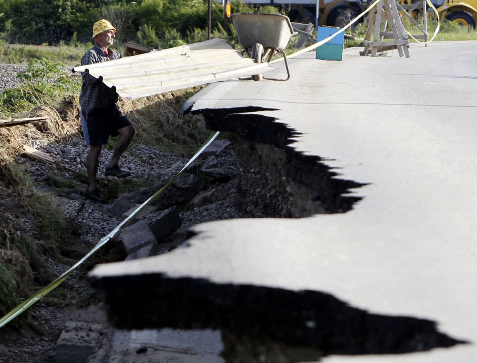 A man is seen next to a damaged road as he collects building materials after heavy floods in Bosanski Samac