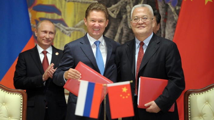 Gazprom CEO Miller and (CNPC) Chairman Zhou shake hands as Russian President Putin looks on during a ceremony in Shanghai