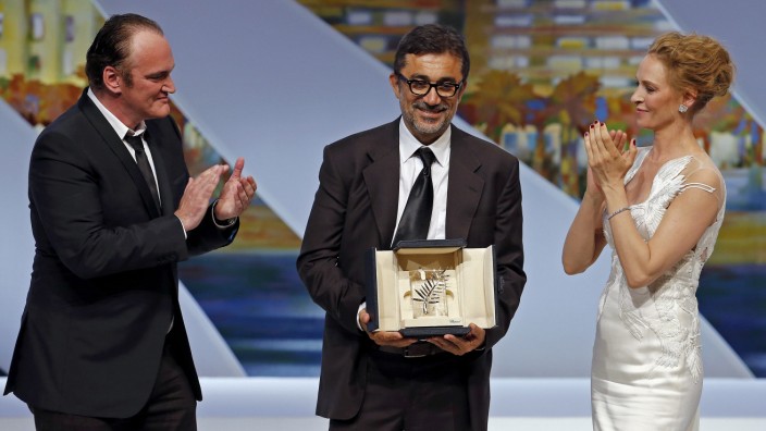 Director Nuri Bilge Ceylan, Palme d'Or award winner for his film 'Winter Sleep', poses on stage next to director Quentin Tarantino and actress Uma Thurman during the closing ceremony of the 67th Cannes Film Festival in Cannes