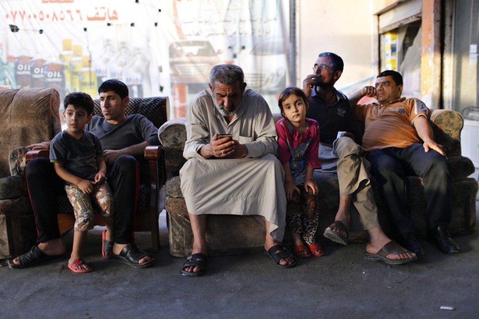 An Iraqi Shi'ite man uses his phone as he sits at an outdoor cafe in Sadr City in Baghdad