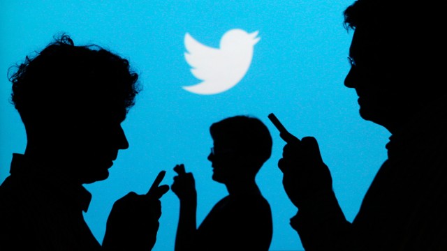 File illustration photo of people holding mobile phones silhouetted against a backdrop projected with the Twitter logo  in Warsaw