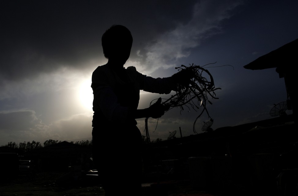 A recycling worker holds wires which she collected from a dismantled microwave in the yard of her tenement house at Dongxiaokou village in Beijing