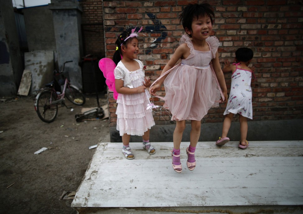 Children play on abandoned wood panels in Dongxiaokou village in Beijing
