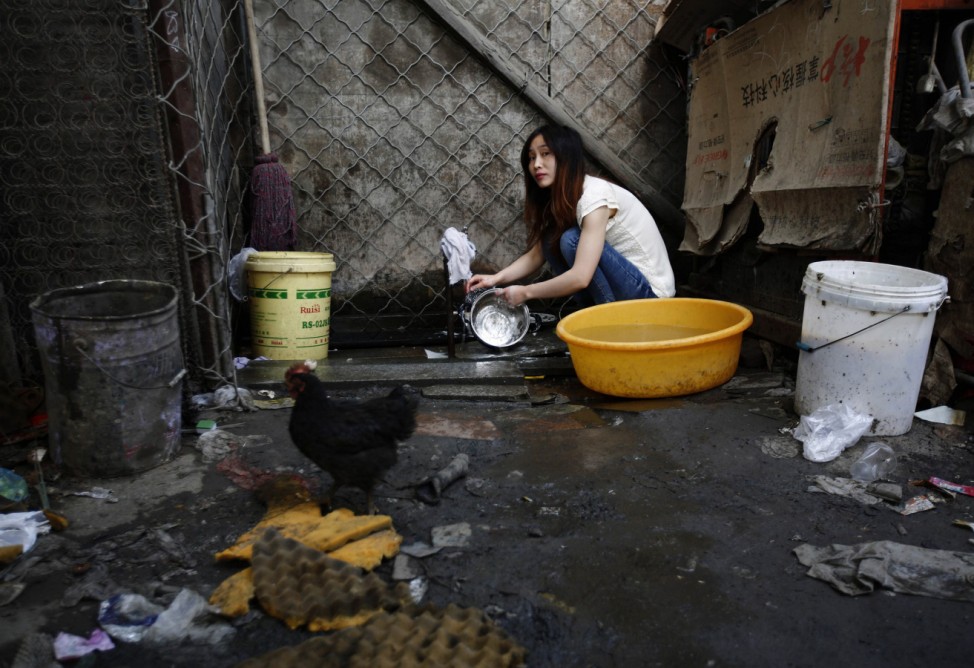 A woman washes dishes at a recycling workers' tenement house in Dongxiaokou village in Beijing