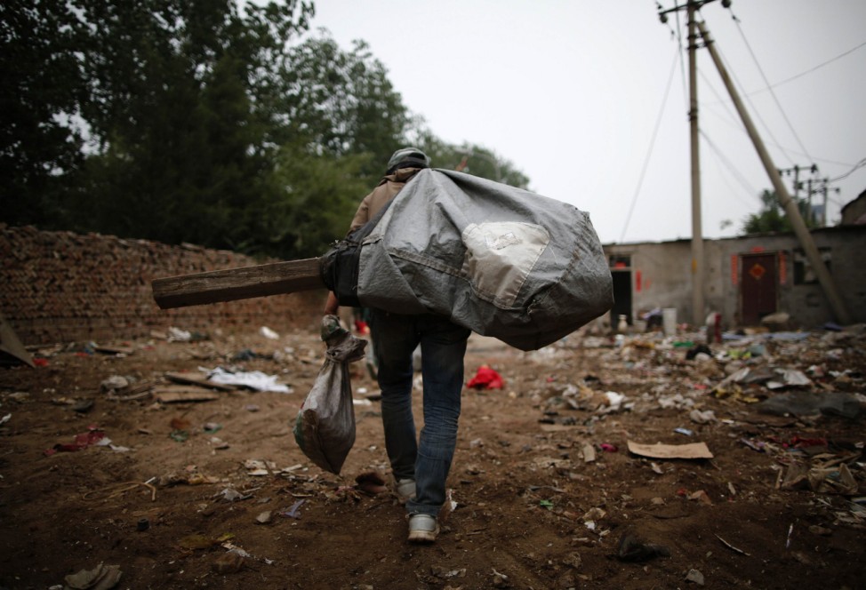A garbage collector carries a sack of of items abandoned by recycling workers at Dongxiaokou village in Beijing