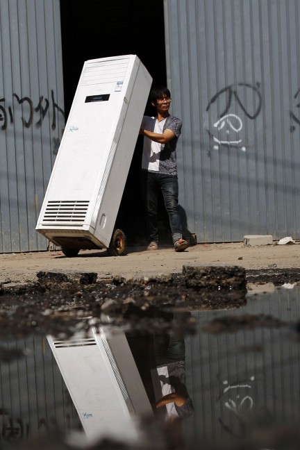 A recycling worker moves an air-conditioning unit in Dongxiaokou village in Beijing