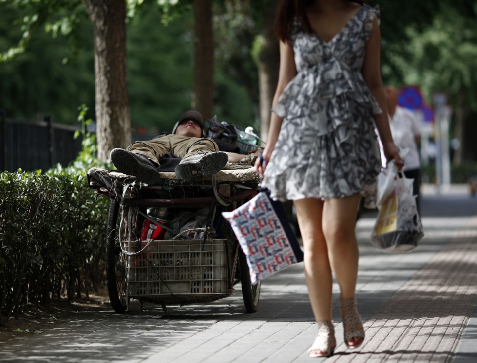 A garbage collector takes a nap on his tricycle, as he waits for people to sell abandoned items to him, in downtown Beijing