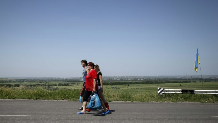 Local residents pass by an Ukrainian servicemen's checkpoint as they leave the eastern Ukrainian town of Slaviansk