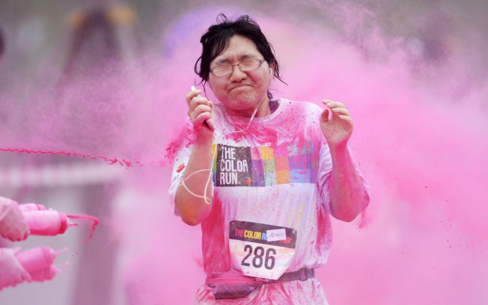 A woman reacts as she is sprayed with colour powder during a five-kilometre colour run event in Beijing