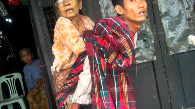 Birma: Ein junger Mann trägt eine ältere Frau im Katastrophengebiet in Birma auf dem Rücken.
