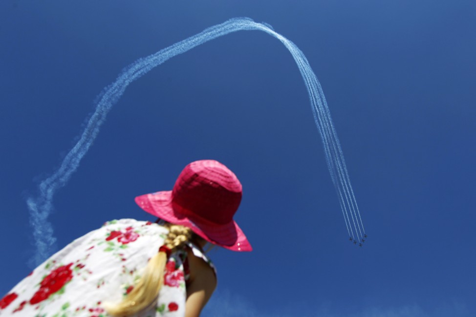 A girl watches Latvia's Baltic Bees aerobatic team performing on L-39C Albatross airplanes during Bucharest International Air Show at Baneasa airport
