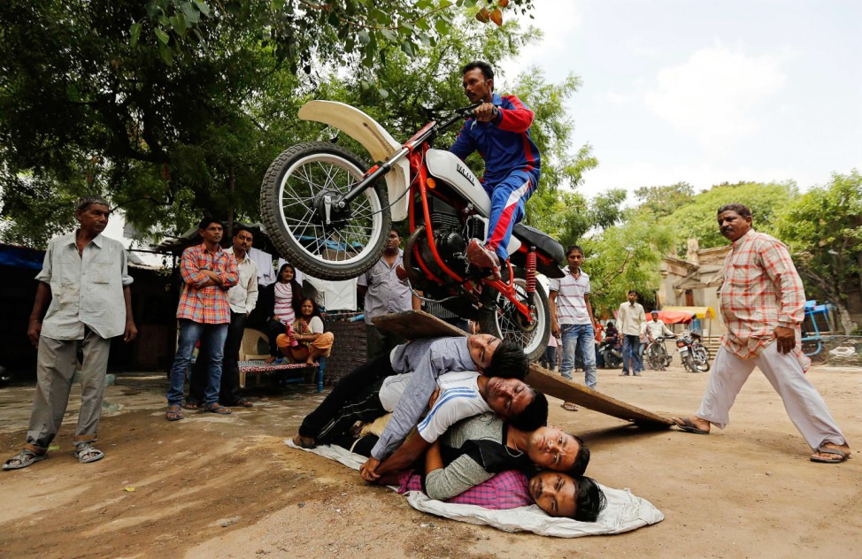 A Hindu devotee performs a stunt with his motorcycle during a rehearsal for the annual Rath Yatra in Ahmedabad