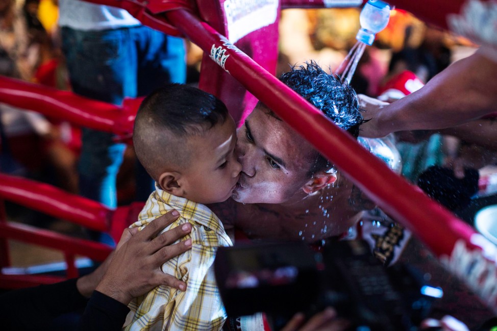 Thai prisoner Sarayuthlek P.U Suphap kisses his son during his fight in 'Fighting Backwall' at Klong Prem Central Prison in Bangkok