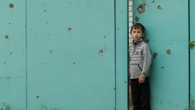 Ukraine-Krise: Ein Junge steht vor dem Tor seines Hauses in der Region Donezk, das während des Waffenstillstandes von ukrainischen Regierungstruppen beschossen worden ist.