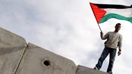 Nahostkonflikt: Schuld am eigenen Schicksal? Ein Palästinenser mit einer Flagge auf der Mauer, die Israel vom Westjordanland trennt.