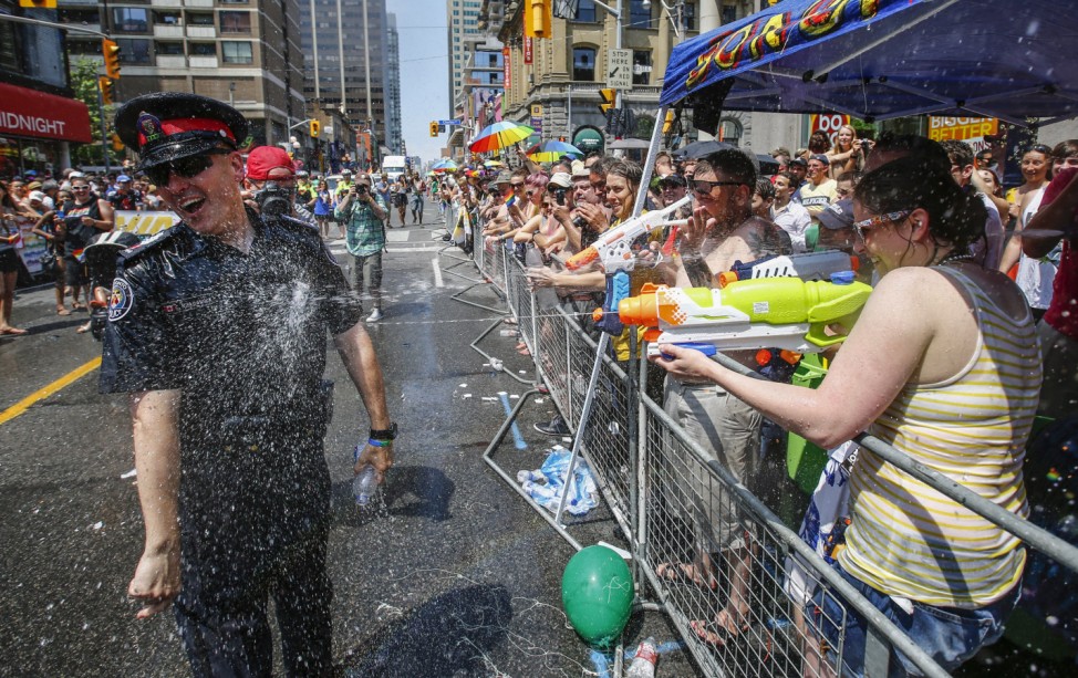 A police officer gets sprayed by water guns during the' WorldPride' gay pride Parade in Toronto