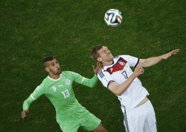 Algeria's Slimani fights for the ball with Germany's Mertesacker during their 2014 World Cup round of 16 game at the Beira Rio stadium in Porto Alegre