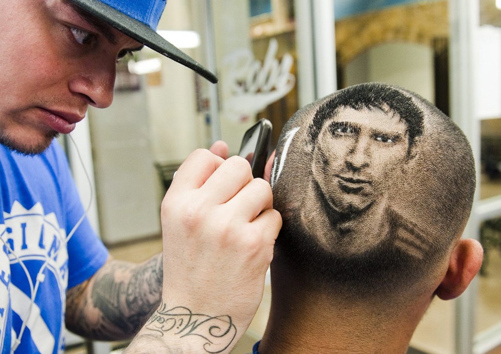 Barber Rob Ferrel known as 'Rob the Original' cuts the likeness of Argentine soccer player Lionel Messi on the head of customer at his barbershop in San Antonio