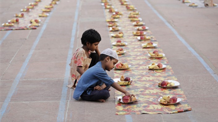 Children sit next to food placed for Muslims before the Iftar meal, during the holy fasting month of Ramadan, at the Jama Masjid in the old quarters of Delhi