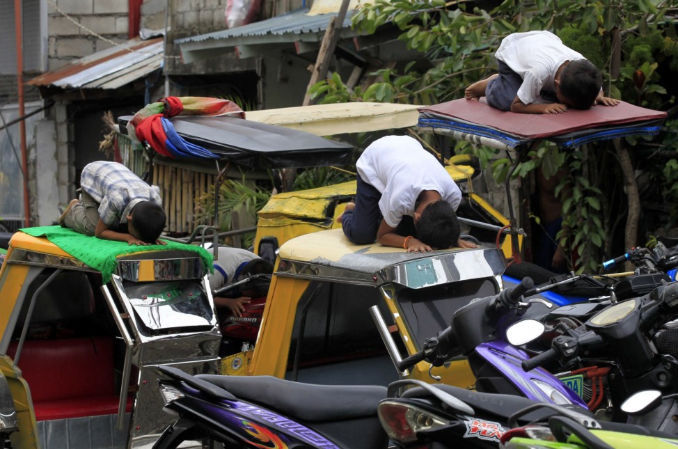 Muslim youths pray atop motorcycle taxis during the fasting month of Ramadan in front of Al-Satie Mosque in Baseco, Tondo city, metro Manila
