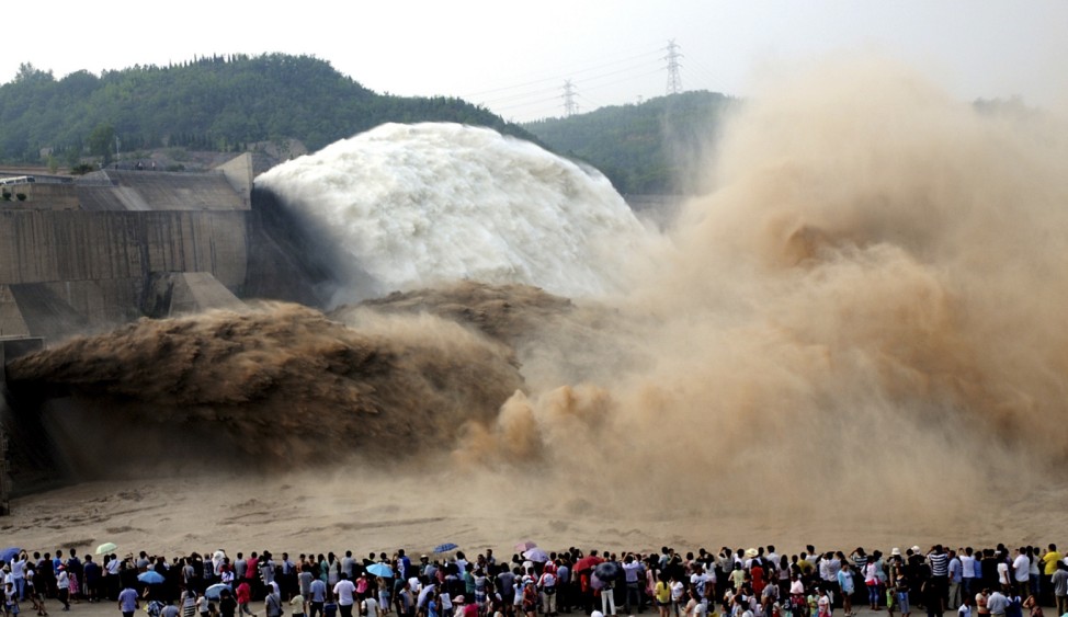 People look on as water gushes from the Xiaolangdi Reservoir section on the Yellow River, during a sand-washing operation in Jiyuan