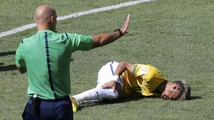 Brazil's Neymar lies injured on the ground as referee Howard Webb of England gestures during their 2014 World Cup round of 16 game against Chile at the Mineirao stadium in Belo Horizonte
