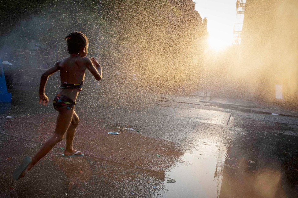 A young girl runs through sprinkler at playground in Brooklyn borough of New York