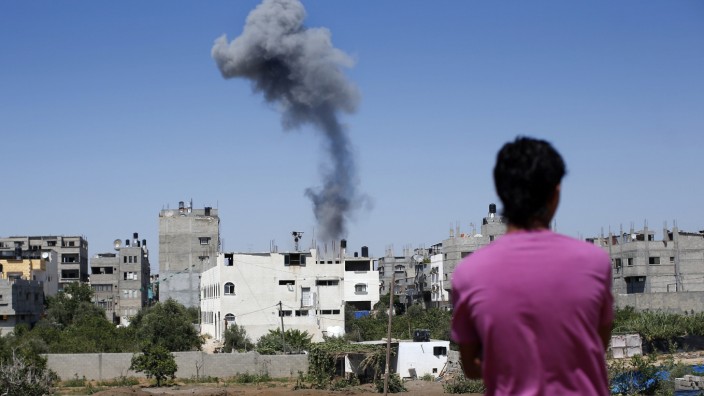 Protokolle aus Gaza und Israel: "Alle fünf Minuten kracht es irgendwo": Ein Palästinenser betrachtet aus der Ferne in Gaza-Stadt die Rauchwolke nach einem Raketeneinschlag