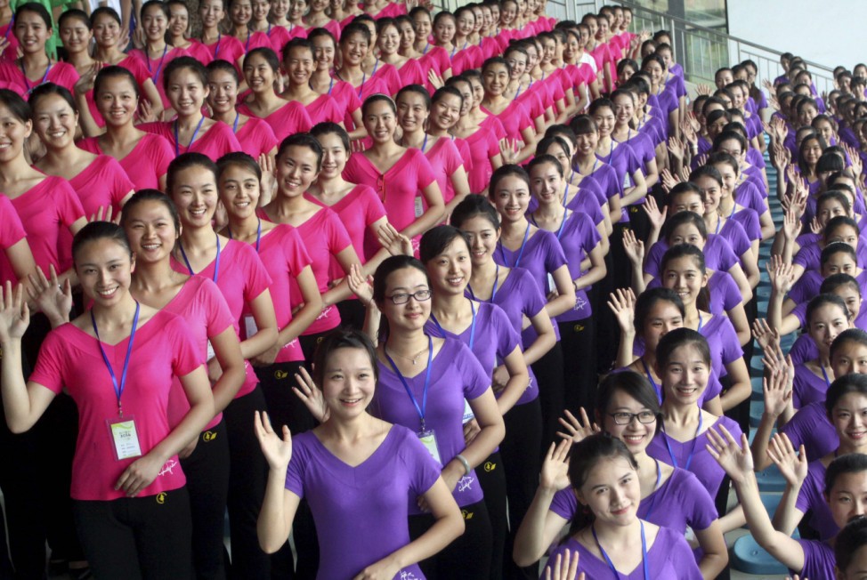 Volunteers, who will be hostesses of Nanjing 2014 Youth Olympic Games, smile and wave during a training in Nanjing, Jiangsu province
