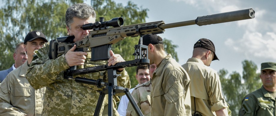Ukraine's President Poroshenko aims a rifle during his visit to a demonstration of new weapons for the Ukrainian armed forces at a military base outside Kiev