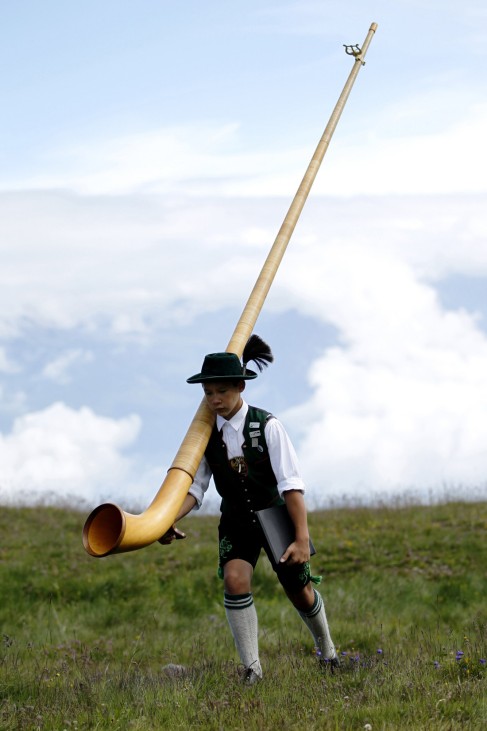 A young Alphorn blower carries his Alphorn before performing an ensemble piece on the last day of the International Alphorn Festival on Lac de Tracouet near the village of Nendaz