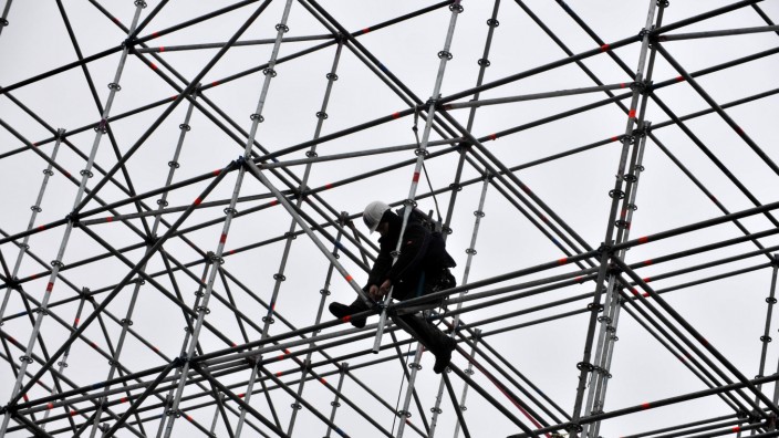 Hohes Risiko: Ein Bauarbeiter steht auf dem Gerüst eines temporären Gebäudes an der Pinakothek der Moderne in München.