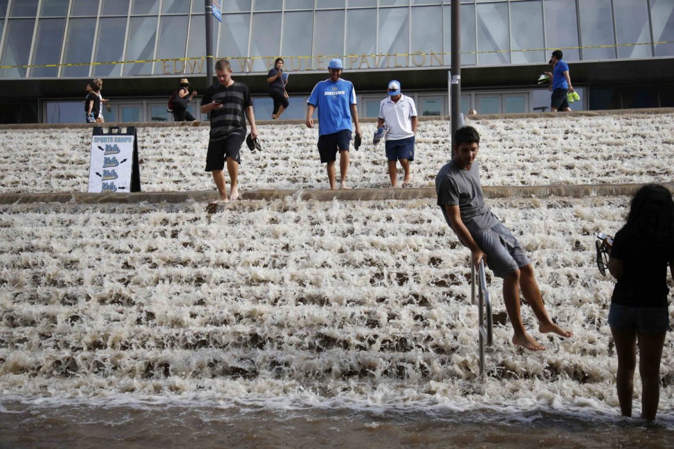 Dominic Aguilera slides down a hand rail into a parking structure outside Pauley Pavilion sporting arena as water flows down stairs from a broken thirty inch water main in Los Angeles
