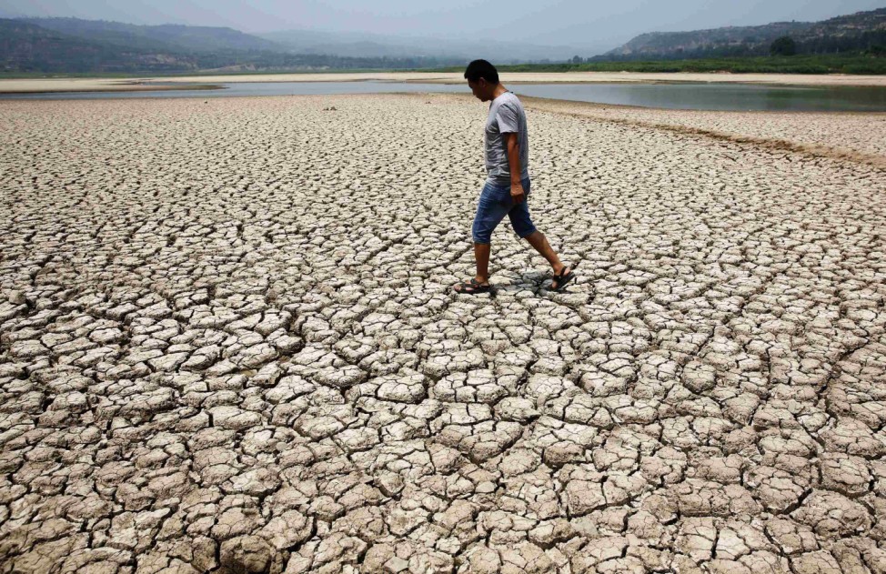 A man walks through the dried-up bed of a reservoir in Sanyuan