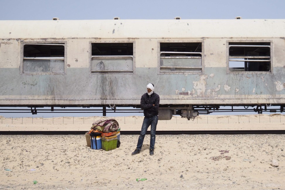 A passenger on a SNIM train carrying iron ore and mine workers waits for transport after arriving in Nouadhibou