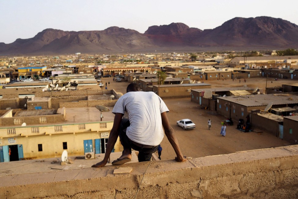 A man climbs down from a rooftop in the iron ore mining town of Zouerate